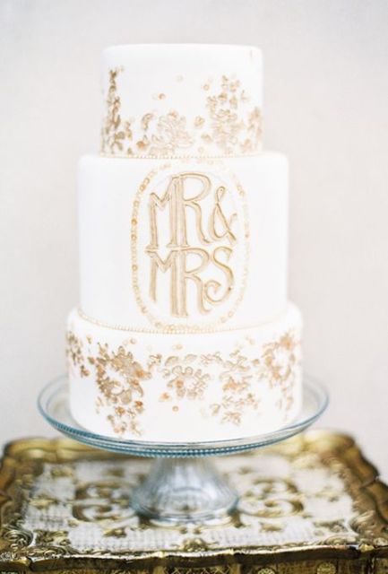 a white wedding cake decorated with gold leaf, with gold monograms is a very chic and beautiful idea to rock, it looks modern and pretty