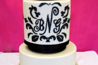 a black and white wedding cake with black ribbons and painted patterns and monograms is a stylish idea for a monochromatic wedding