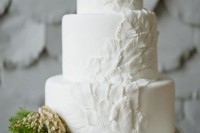a romantic plain white wedding cake with feathers going up the cake is a very chic and elegant idea