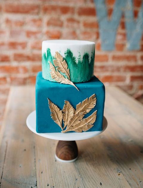 a bright square and round wedding cake in blue and teal, with gold feathers for detailing is a bold and cool idea
