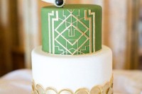a chic art deco wedding cake with gold scallops, a green and gold geometric tier, white feathers and a black rhinestone