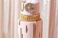 a pink art deco wedding cake with edible beads, gold scallops and an oversized brooch plus a giant feather