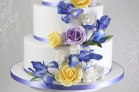 a refined white wedding cake decorated with blue ribbons, sugar white, yellow, blue roses and blue irises is a lovely idea