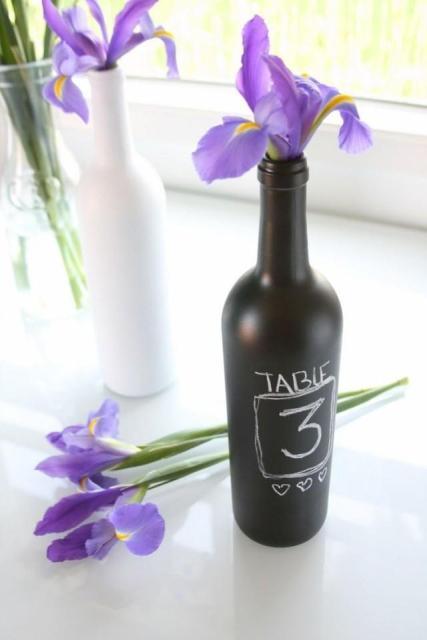 a chalk painted bottle with a chalked table number and a blue iris is a cool decoration that you can easily DIY