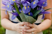 a beautiful blue iris wedding bouquet with leaves and a white wrap with pearly buttons is a great idea for a bold wedding