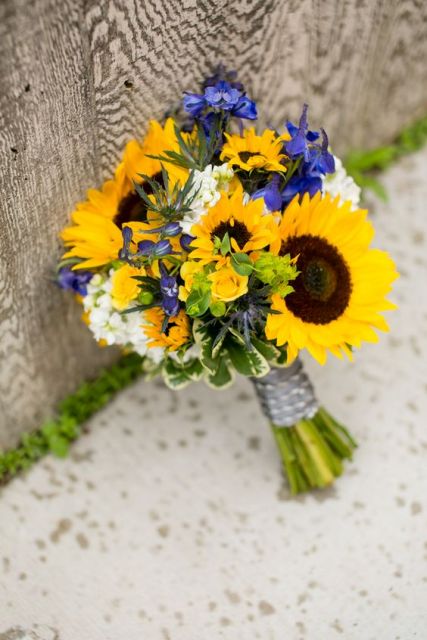 a bold rustic wedding bouquet of white blooms, sunflowers and some irises is a cool idea for a fun rustic wedding