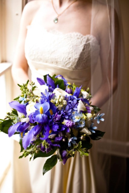 a bold wedding bouquet of blue irises, neutral blooms and greenery is a colorful solution for a modern wedding