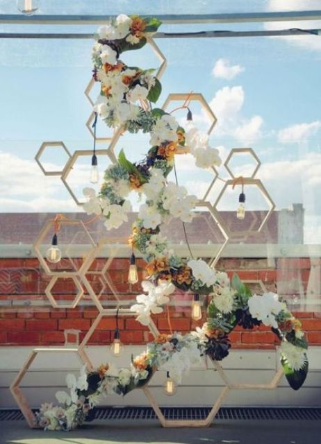 a honeycomb wooden shelf decorated with white and rust blooms, greenery and bulbs hanging down is a pretty wedding backdrop for your ceremony and not only