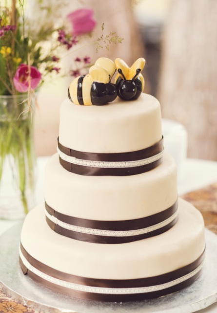 a black and white wedding cake topped with large bee toppers is a lovely idea for a fun wedding