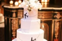 a black and white wedding cake topped with fresh blooms and with planes to mark that it’s a travel-themed wedding