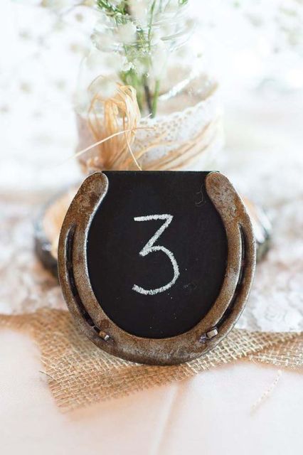 a horse shoe table number with a chalkboard is a cool and simple rustic idea for a wedding