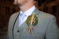 a wedding boutonniere of a leaf, a spike, baby’s breath and a horseshoe and twine