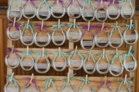 rustic wedding favors – horseshoes with turquoise and purple bows attached with clothespins to a pallet