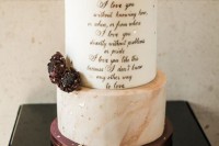 a sophisticated wedding cake with peachy marble tiers and a white one with calligraphy, gold leaf and dark blooms for a romantic wedding