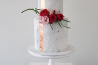 a classic white marble wedding cake with a copper ribbon and bold blooms and greenery is modern