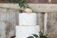 a neutral marble wedding cake decorated with greenery and a sugar bloom is a modern rustic wedding idea