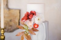 a grey marble and plain white wedding cake decorated with bold and neutral blooms and a bright fall leaf for a sophisticated wedding