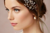 a simple and messy low updo with a sleek top and a beautiful rhinestone hairpiece for an accent