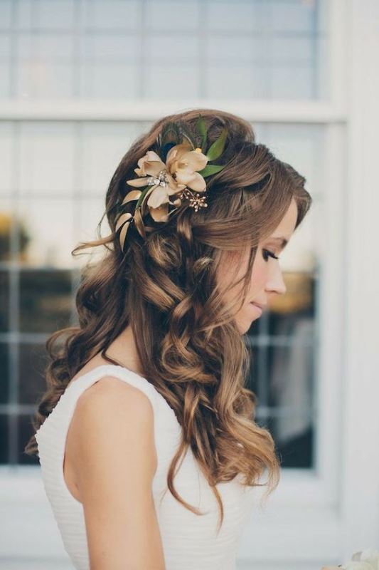 a wavy and curly hairstyle with faux blooms and greenery is a timeless and stylish idea for a bride