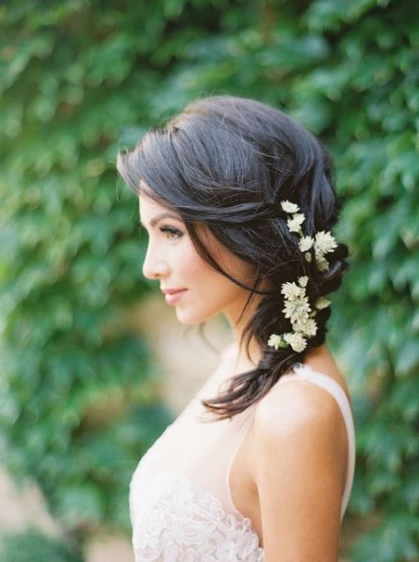 a messy side braid with some fresh blooms tucked in is a great relaxed wedding hairstyle to try