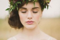 a wavy and a bit messy side low updo with a greenery and moody flower crown for a romantic fall bridal look