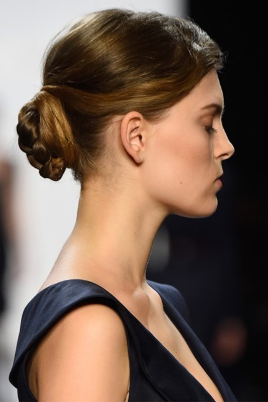a stylish low updo   a braided and twisted low bun with a bump on top is a timeless idea for a bride