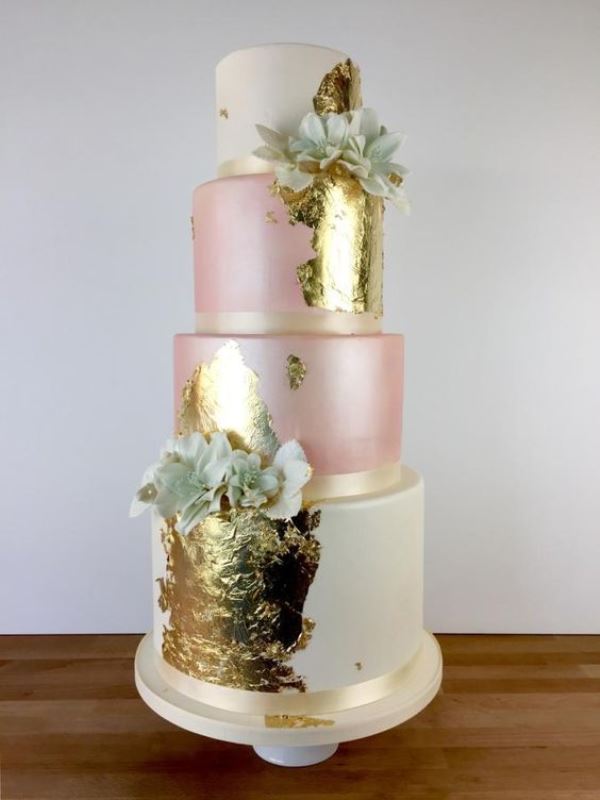 a statement wedding cake in ivory and pink, with lots fo gold leaf and edible flowers to accent it