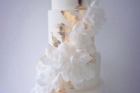 a white wedding cake decorated with gold leaf, with white sugar blooms looks very refined and very formal
