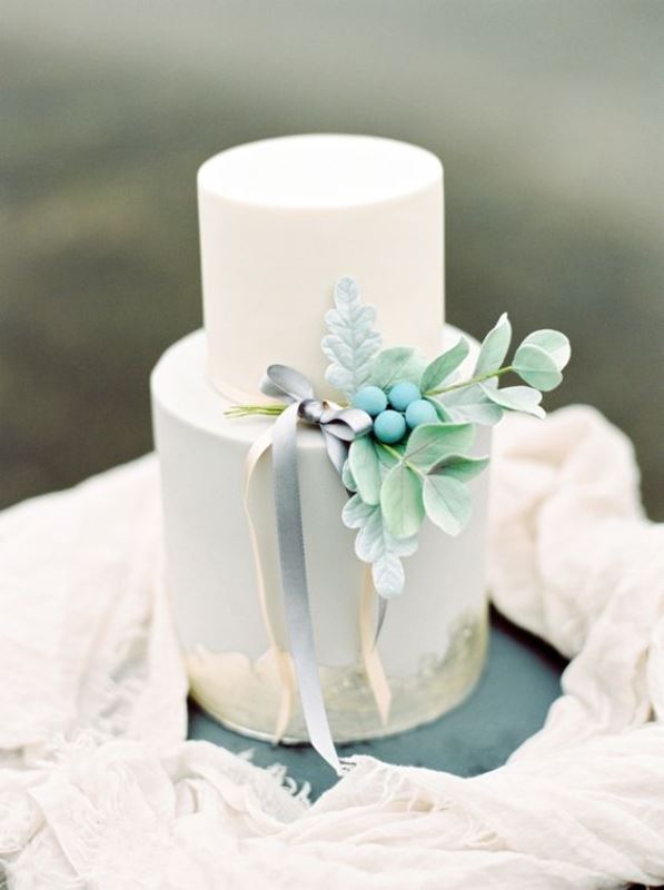 a delicate wedding cake in white and powder blue, with with sugar leaves, berries and some ribbons is a perfect fit for spring