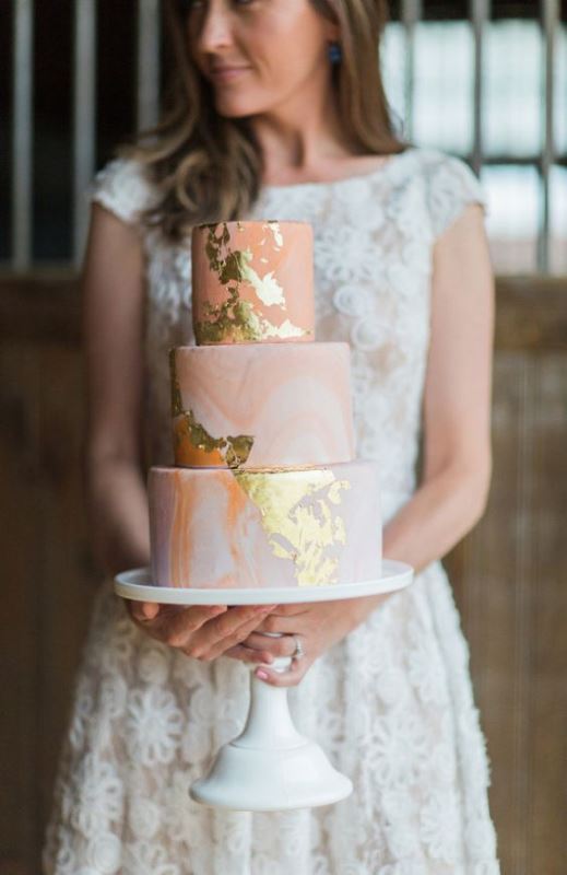 a trendy peachy marble wedding cake with gold leaf is a chic and cute idea for a modern wedding
