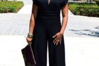 a black jumpsuit with wideleg pants, cape sleeves, a high waist and a statement necklace