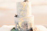 a blue watercolor wedding cake with gold leaf, privet berries and blush blooms looks delicate and chic