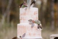 a blush drip wedding cake with succulents, dark foliage and feathers for a boho wedding