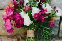 a bold and contrasting wedding bouquet of white blooms, purple freesias, blue thistles and greenery and a burlap wrap