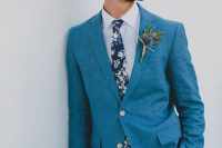 a bold blue suit, a dark floral tie, a white shirt and a man bun for a relaxed and very stylish groom’s look