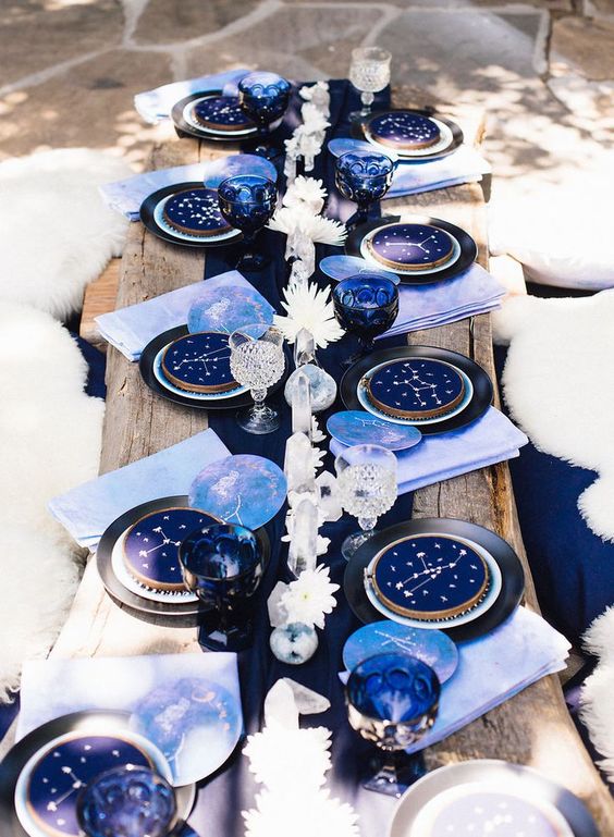 a bold puple and navy wedding tablescape with white blooms, constellation plates, lilac napkins and a navy runner