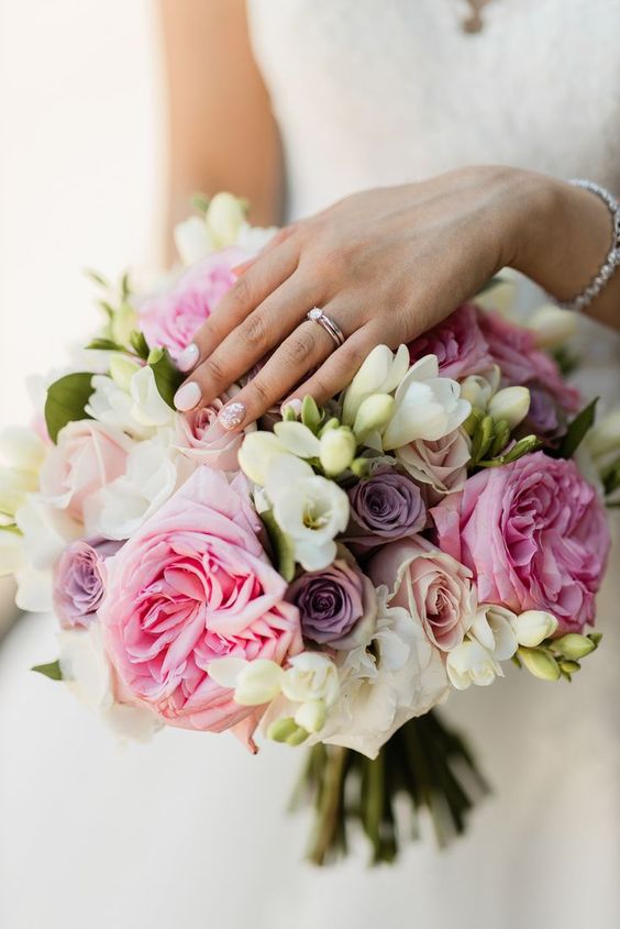 a bright wedding bouquet of roses, freesia and peony roses in lilac, pink and blush plus white for a bright wedding