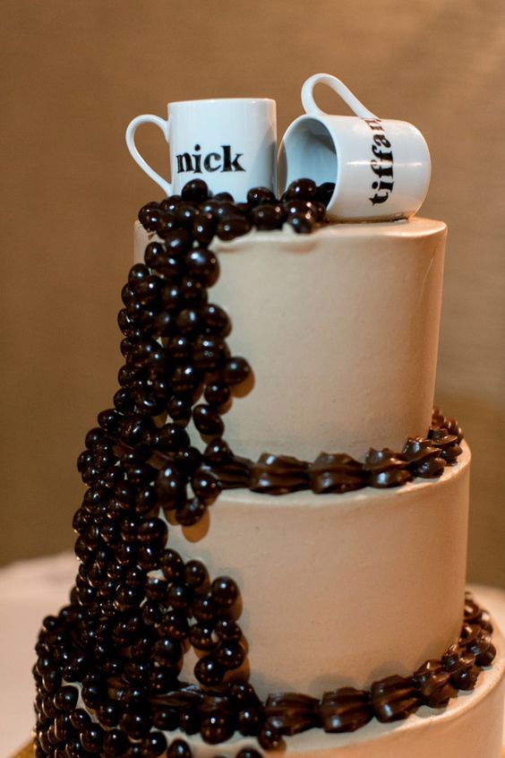 a buttercream wedding cake topped with edible coffee beans and with coffee mugs on top is a fun idea
