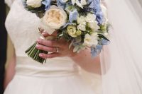 a catchy wedding bouquet of blue and white freesia, white roses and peony roses and greenery for your something blue