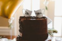 a chocolate wedding cake with coffee beans and coffee mugs on top is a cool idea for a coffee-loving wedding