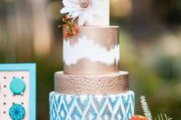 a colorful boho wedding cake with a navy, ikat, copper and white tier, a bloom and feathers
