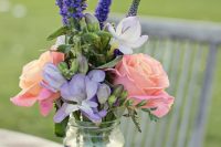 a colorful wedding centerpiece of pink roses, lilac freesias, lisianthus and greenery for a bright summer wedding