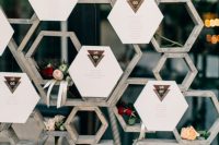 a creative seating chart built of wooden honeycombs and honeycombs of paper showing off the seating plan is cool for a rustic wedding