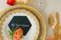 a creative wedding place setting with honeycomb plates and a black honeycomb card and bold blooms and gold cutlery