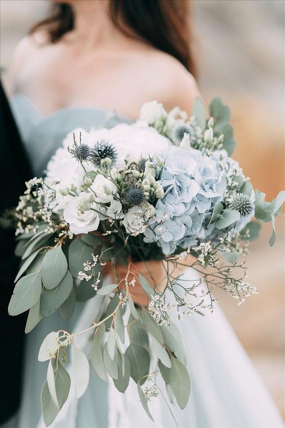 a delicate wedding bouquet of white roses and blue hydrangeas, eucalyptus, allium and some waxflower is a dreamy solution for a spring bride