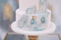 a delicate white and watercolor blue wedding cake with gold leaf is a stunning idea for a celestial or coastal wedding