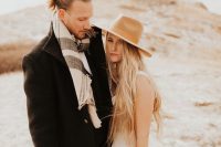 a fall boho groom look with a black coat, a striped scarf and a messy man bun on top to look more relaxed and casual