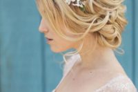 a girlish wavy low updo with a bump and some waves down plus a floral crown looks amazing