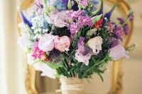 a gorgeous wedding bouquet with lilac roses, purple freesias, blue and purple blooms, lisianthus and greenery for a colorful wedding