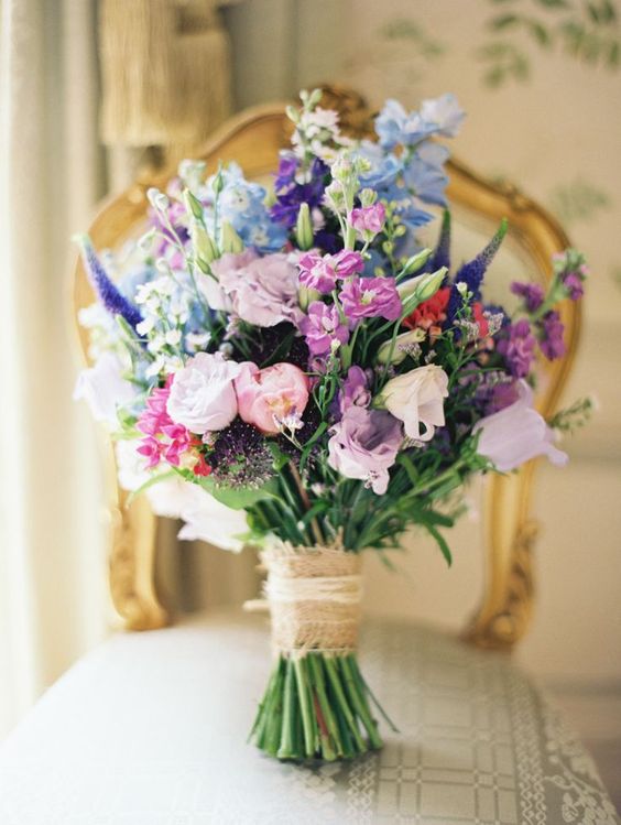 a gorgeous wedding bouquet with lilac roses, purple freesias, blue and purple blooms, lisianthus and greenery for a colorful wedding